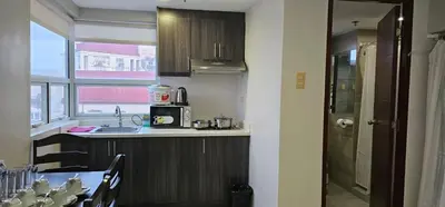 a kitchen with a counter and a sink and a table at Homes by Gilmore Tower Suites in Manila