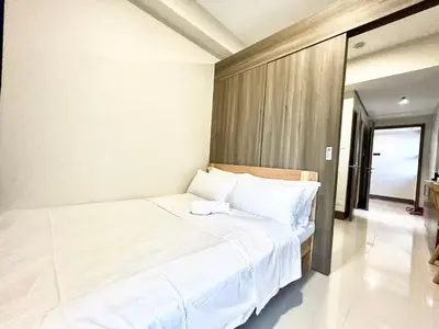 a bedroom with a large white bed with white sheets at Cairong Inn Condominium TV with Netflix FAME RESIDENCES in Manila