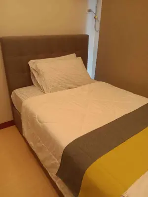 a bed with a brown headboard and white sheets at Homey 1Bedroom BGC Condo - MINIMUM 2 Nights stay in Manila