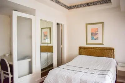a white bedroom with a bed and a mirror at Sunette Tower Suites Makati City Center in Manila