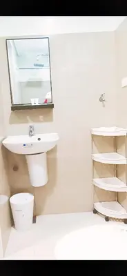a white bathroom with a sink and a mirror at Shore 2 Residences 1BR Deluxe Room in MOA Complex in Manila