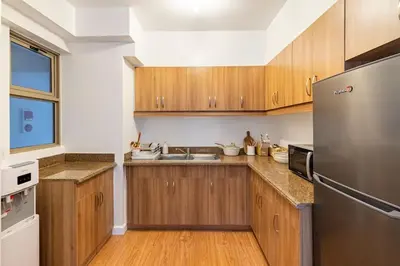 a kitchen with wooden cabinets and a stainless steel refrigerator at Bohemian Inspired 2 Bedroom Inspired Condo with Fast WIFI Near BGC in Manila
