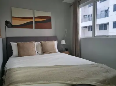 a bedroom with a large bed and a window at Homey condo unit in BGC - B SOMA NT in Manila