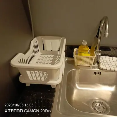 a kitchen sink with a dish drying rack next to it at Cozy New 1BR Fame Residences Condo with Balcony in Manila