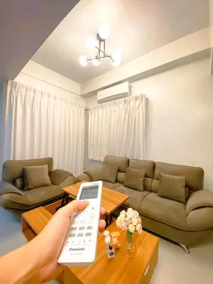 a person holding a remote control in a living room at Deluxe Room w/ Pool & Billiards in Manila