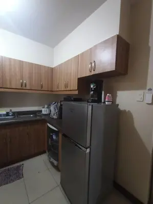 a kitchen with a stainless steel refrigerator and wooden cabinets at Available Resort Type Condo Unit in Manila