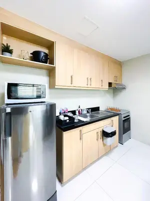 a kitchen with a stainless steel refrigerator and wooden cabinets at Hotel like unit The Avant at the Fort in Manila