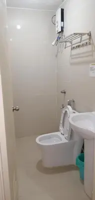 a white bathroom with a toilet and a sink at Meaco Royal Hotel - Biñan Laguna in Biñan