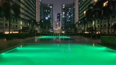 a pool of green water in a city at night at The New Villa at Sea Residences in Manila