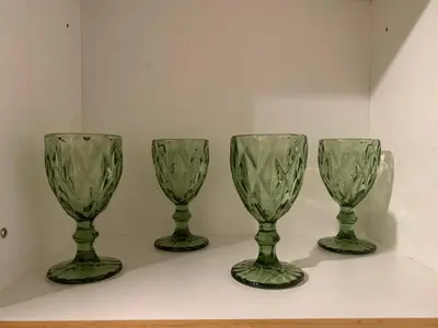 four green glass wine glasses sitting on a shelf at Shell Residences Mall of Asia Pasay in Manila
