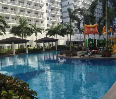 a large swimming pool with a playground in front of a building at Shell Residences Mall of Asia Pasay in Manila