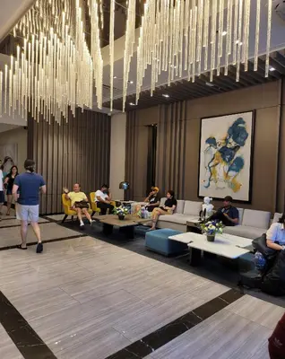 a lobby with people sitting around tables and chandeliers at Uptown Parksuites Tower 1 at BGC - Staycations Up Above 12 in Manila