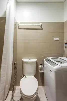 a bathroom with a white toilet and a sink at BTS Be The Ace at MOA in Manila