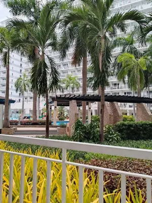 a white fence with palm trees in front of a building at Shell Residences 2BR & 2CR 101D in Manila