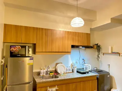 a kitchen with wooden cabinets and a stainless steel refrigerator at Cozy 1 BR Scandinavian/Tropical Condo with Balcony & Parking in Manila