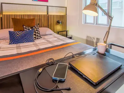 a bedroom with a bed with a tablet on a desk at Relaxing Apt Bgc Business Ready with 84inch Cinema in Manila