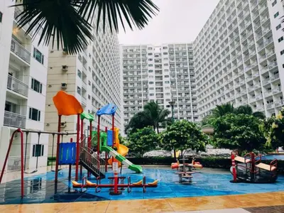 a pool with a playground in a city with tall buildings at MOA Arena 1155 CONDOTEL DYNASTEL SHORE in Manila