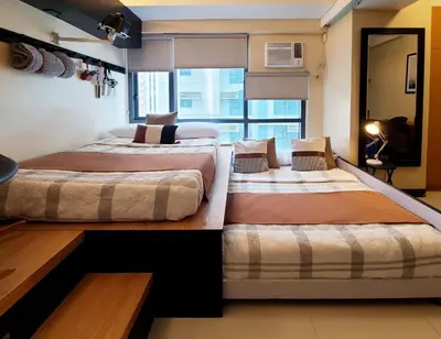 two beds in a room with a large window at Max Dwell Bgc Creative Space with 84 