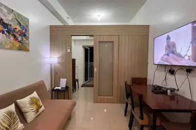 a living room with a couch and a table and a tv at Direct Pool Access Shore Residences MOA Pasay Near Airport in Manila