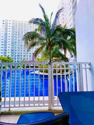 a view of the ocean from a balcony with a palm tree at Direct Pool Access Shore Residences MOA Pasay Near Airport in Manila