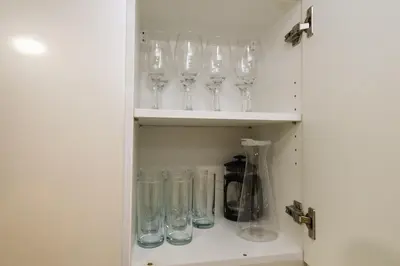 a cupboard filled with glasses and a blender at Spacious 2BR Apartment in BGC with Workspace & Washer in Manila