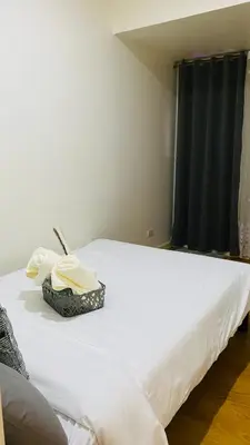 a white bed in a room with a black curtain at cozy and minimalist room near airport in Manila