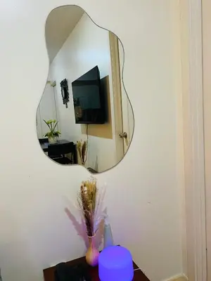 a mirror on a wall with a vase on a table at cozy and minimalist room near airport in Manila