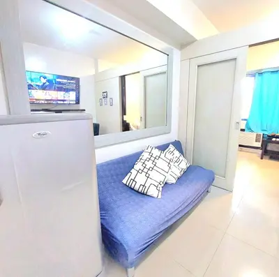 a blue couch in a kitchen with a refrigerator at Sea Residences by Jan & Val Alano in Manila