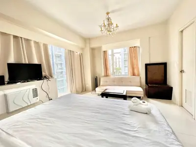 a white bedroom with a large bed and a couch at Cozy Spacious Condo Hotel near NAIA Manila Airport Pasay in Manila