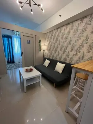a living room with a black couch and a table at BH Crib - Staycation near Mall of Asia Complex in Manila