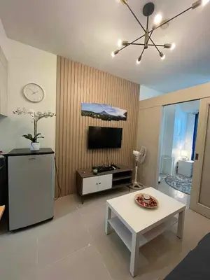 a living room with a tv and a white table at BH Crib - Staycation near Mall of Asia Complex in Manila