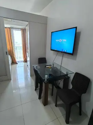 a dining room with a glass table and a flat screen tv at BH Crib - Staycation near Mall of Asia Complex in Manila