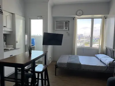 a bedroom with a bed and a desk and a table at Studio Getaway in Alabang at Anuva Residences in Manila