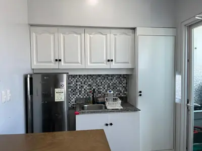 a kitchen with white cabinets and a refrigerator at Studio Getaway in Alabang at Anuva Residences in Manila