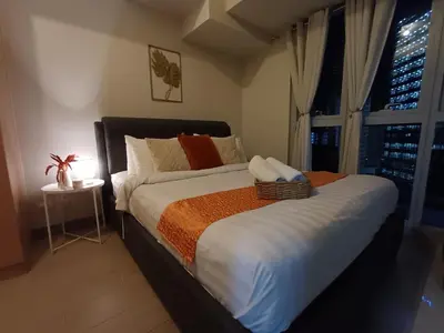 a large bed in a bedroom with a window at Cozy Pad BGC in Manila