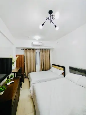 a bedroom with two beds and a flat screen tv at Hotel Luxury Twin Bed Room with Balcony Las Pinas-South Residence in Manila