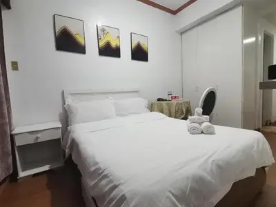 a bedroom with a white bed with a stuffed animal on it at romantic makati in Manila
