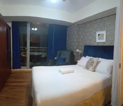 a bedroom with a large white bed with a blue headboard at Azure Urban Residence A11 Near Airport and SM Bicutan+ Free wifi in Manila