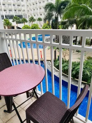 a balcony with a table and chairs and a pool at SHORE RESIDENCE D15 shortwalk Mall of asia near airport in Manila