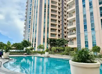 a swimming pool in front of a tall building at Cozy Place @ Venice Luxury Residences in Manila