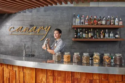 a man standing behind a bar with a bottle at F1 Hotel Manila in Manila