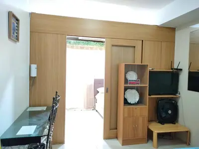 a living room with a sliding glass door with a television at Magayon Staycation Shell Residences Mall of Asia in Manila