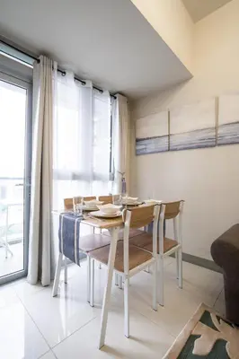 a dining room with a table and chairs and a window at 2BR 2TB Uptown Parksuites BGC Balcony,fast WiFi,Washer in Manila