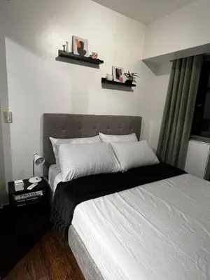 a bedroom with a bed with two shelves on the wall at Prime Posh Downtown Condo in Manila