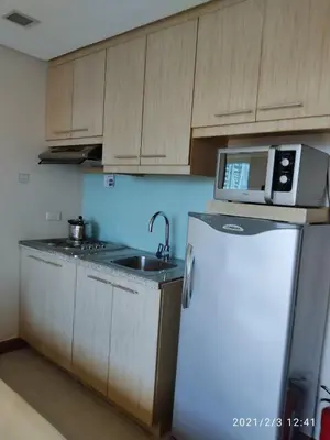 a kitchen with a sink and a microwave above a refrigerator at Twin Beds Studio Room with City View in Manila