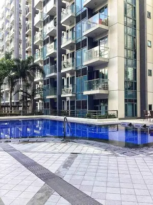 a building with a swimming pool in front of a building at Palm Tree Villas in Manila