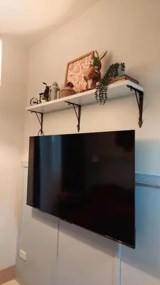 a television with two shelves on top of a wall at My Humble Abode at Shore 3 in Manila