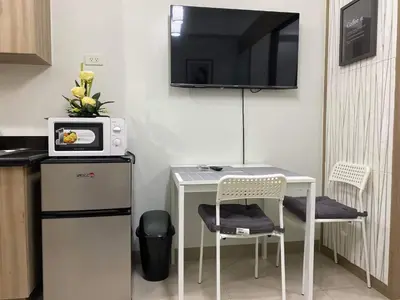 a small kitchen with a table and a tv on the wall at SHORE RESIDENCE D16 shortwalk Mall of asia near airport in Manila
