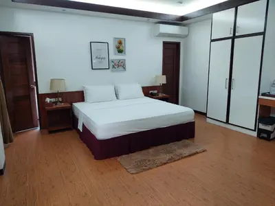a bedroom with a bed with white sheets and wooden floors at MaClare Resort in Imus