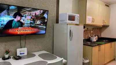 a kitchen with a refrigerator and a tv on the wall at CHATEAU ELYSEE A16 Near Resto And Sm Mall/Airport in Manila